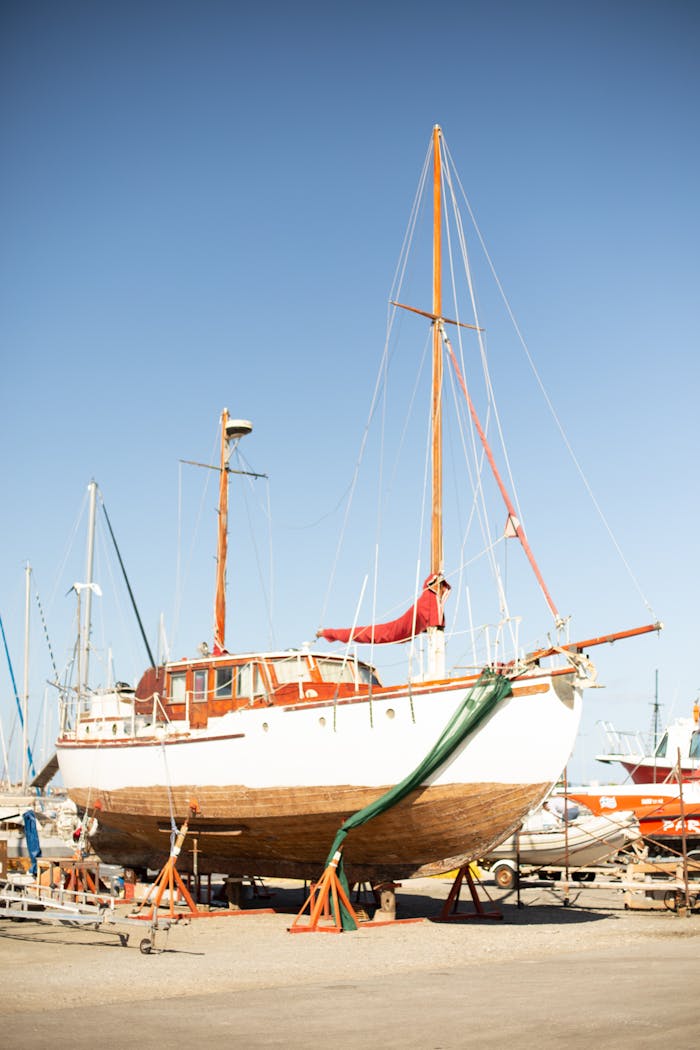 A classic wooden sailboat docked in a Greek shipyard on a sunny day.